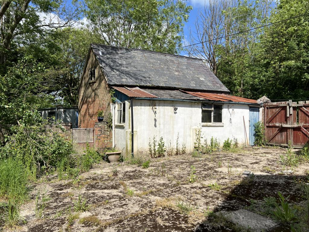 Lot: 129 - FOUR-BEDROOM HOUSE IN NEED OF IMPROVEMENT - Concrete patio in rear garden with garage and gates to road